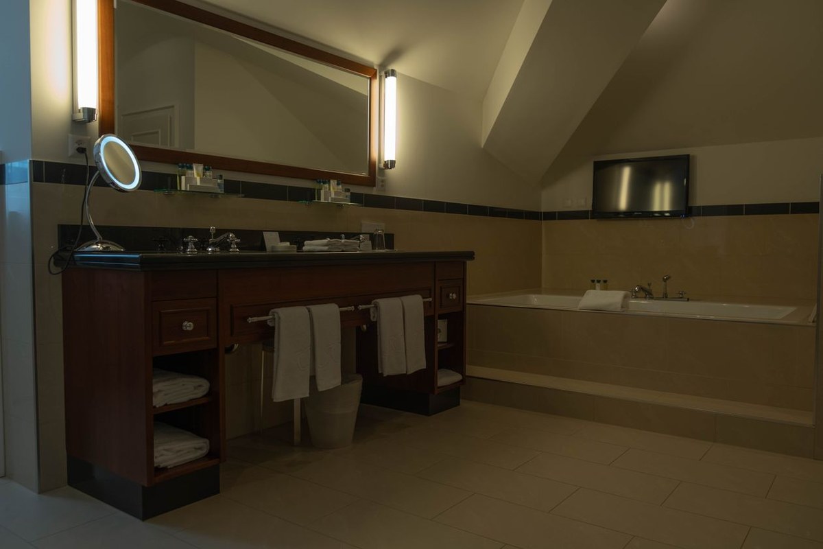 Luxury bathroom with large-format beige wall and floor tiles, dark wood vanity, and built-in tub